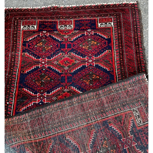 1653 - A Kazak carpet with repeating stepped medallions in reds and blues, 172cm x 92cm approx.