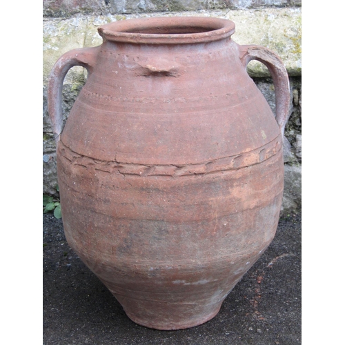 2074 - A weathered terracotta squat oviform jar with moulded loop handles and incised pressed banded detail... 