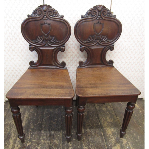 2621 - A pair of Regency mahogany hall chairs, the shaped backs with C scroll, acanthus and other detail, o... 