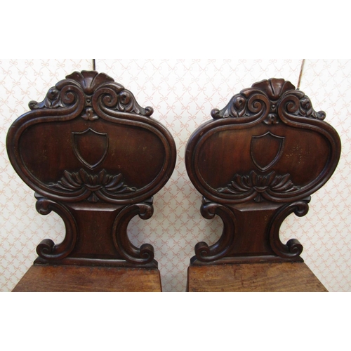 2621 - A pair of Regency mahogany hall chairs, the shaped backs with C scroll, acanthus and other detail, o... 