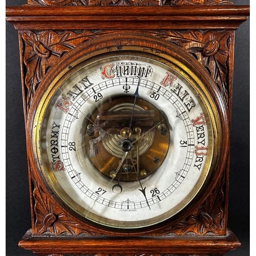 1378 - An Edwardian aneroid barometer in a profusely carved shaped oak case, with enamelled dials