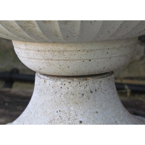 2002 - A set of three weathered cast composition stone squat circular fluted garden urns, with fixed bases,... 