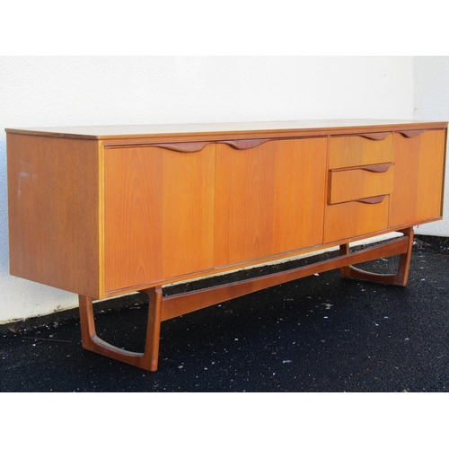 2497 - A teak sideboard enclosed by three cupboard doors and three drawers on an open framework, 205 cm len... 