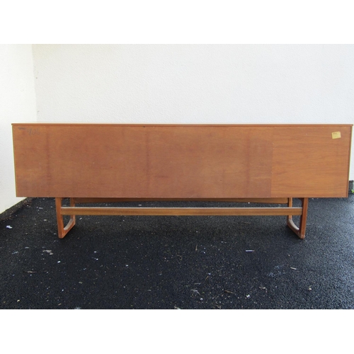 2497 - A teak sideboard enclosed by three cupboard doors and three drawers on an open framework, 205 cm len... 