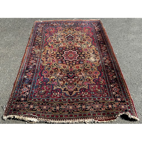 1647 - An old Persian carpet with a central floral medallion on a field of flowers, 104cm x 74cm approx.