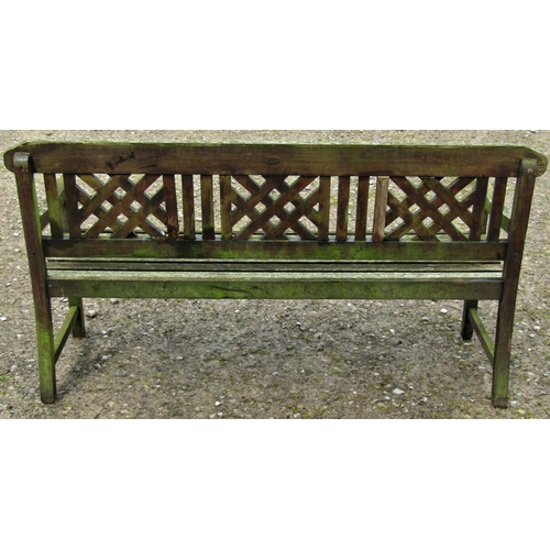 7 - A weathered hardwood three seat garden bench with slatted seat beneath a decorative lattice panelled... 