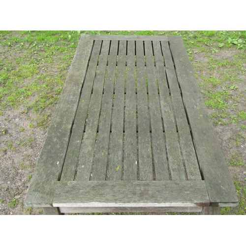 33 - A weathered teak garden table with rectangular slatted panelled top raised on square tapered support... 