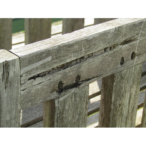 139 - A weathered hardwood garden bench with slatted seat, back and curved arms, (stamped to back rail www... 