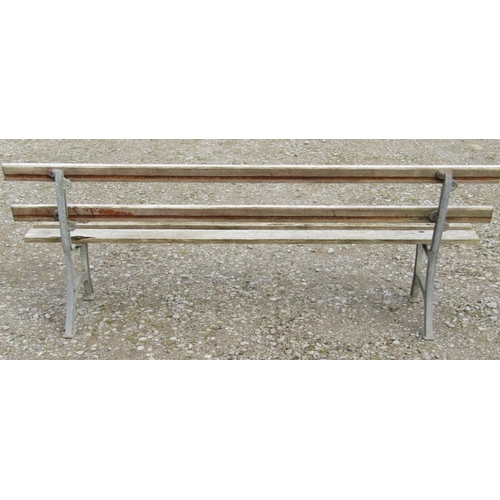 160 - A garden bench with simple weathered slatted wooden seat and back rails raised on cast alloy support... 