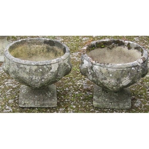 172 - A pair of well weathered cast composition stone squat circular garden urns with fixed square based s... 