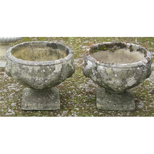 172 - A pair of well weathered cast composition stone squat circular garden urns with fixed square based s... 