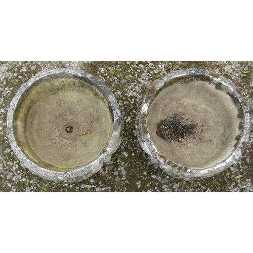 172 - A pair of well weathered cast composition stone squat circular garden urns with fixed square based s... 