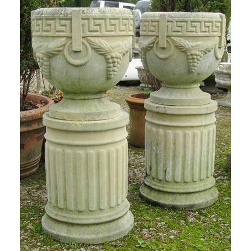 179 - A pair of weathered cast composition stone garden urns, the circular waisted bowls with Greek key, r... 