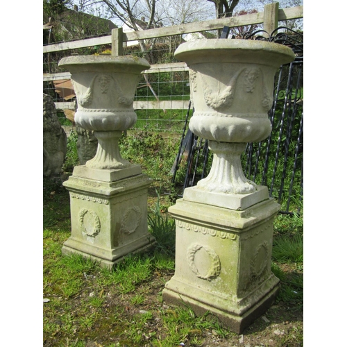 184 - A pair of weathered cast composition stone garden urns with flared rims, repeating face mask and fru... 