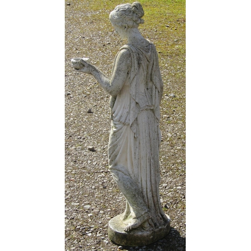 204 - A weathered cast composition stone ornament in the form of a classical standing maiden holding out a... 