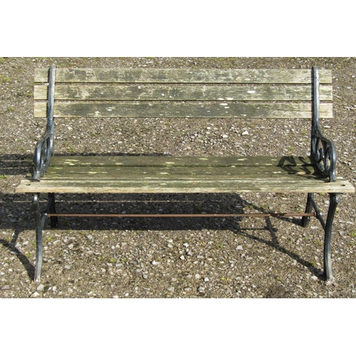36 - A two seat garden bench with weathered wooden lathes raised on decorative pierced cast iron end supp... 