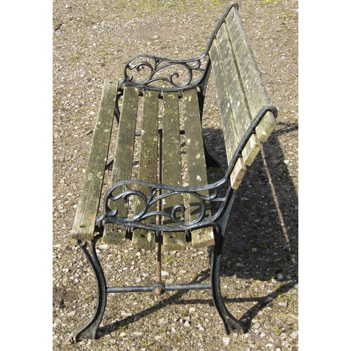 36 - A two seat garden bench with weathered wooden lathes raised on decorative pierced cast iron end supp... 