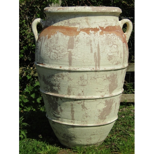 73 - A large ribbed terracotta jar with moulded loop handles and all over painted and distressed finish, ... 