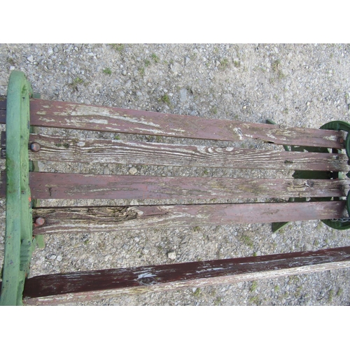 94 - A garden bench with stained wooden lathes, raised on a pair of green painted 19th century bench ends... 