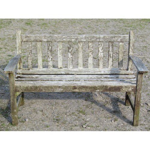 95 - A weathered Gloster teak two seat garden bench with slatted seat and back, 129cm wide, together with... 