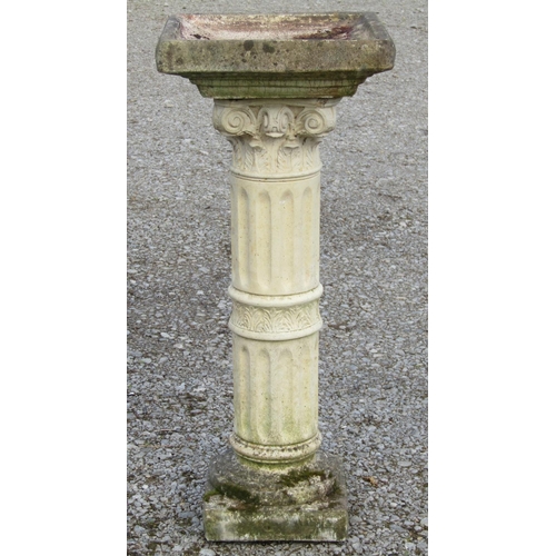 218 - A weathered cast composition stone two sectional bird bath, the square top raised on a fluted cylind... 