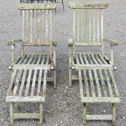 232 - A pair of weathered teak folding steamer type garden lounge chairs with slatted seats, backs and fol... 