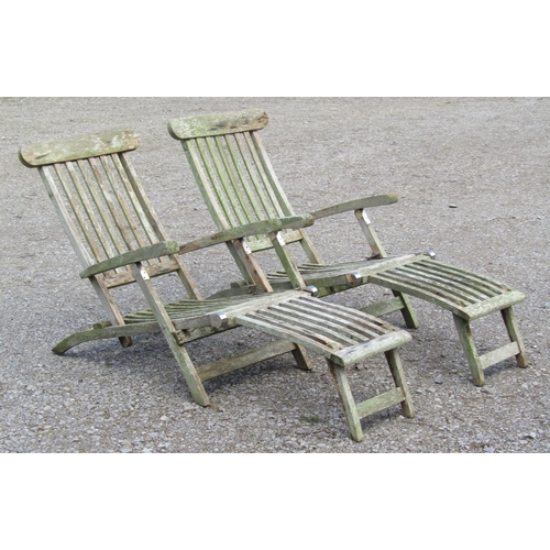 232 - A pair of weathered teak folding steamer type garden lounge chairs with slatted seats, backs and fol... 