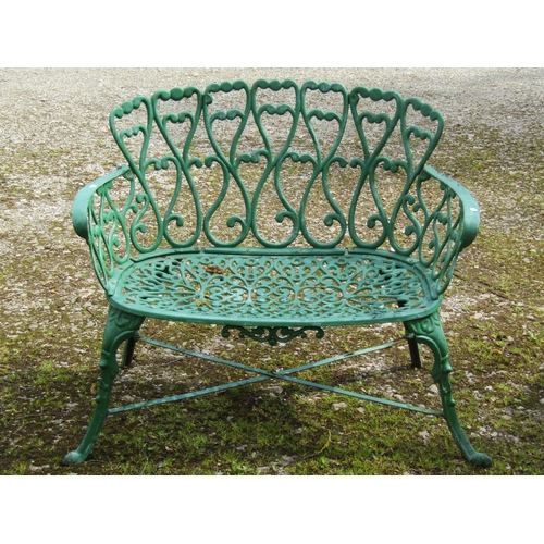 234 - A small decorative green painted cast iron garden bench with repeating pierced open scroll foliate p... 