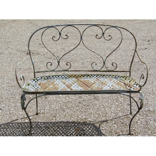 235 - A weathered decorative iron work two seat garden bench with lattice strapwork seat and open scroll d... 