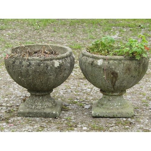 88 - A pair of weathered cast composition stone garden urns with squat circular lobed bowls raised on fix... 