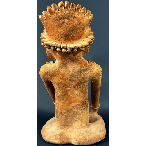 2052 - A South American pottery figure of a seated cross legged character with feathered headdress