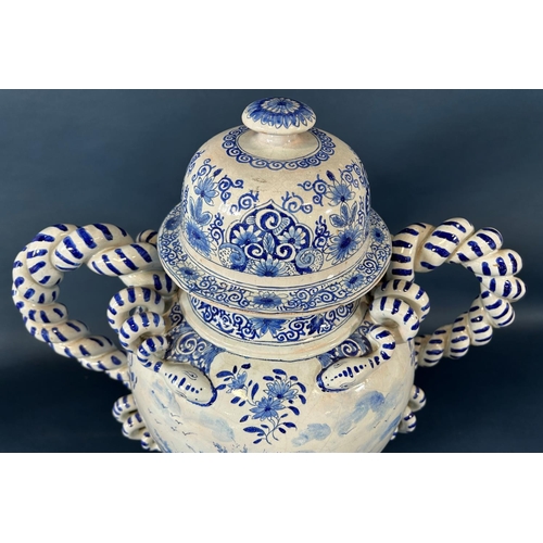 2063 - A substantial continental tin glazed urn and cover in a blue and white colourway with hand painted s... 