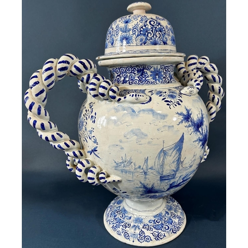 2063 - A substantial continental tin glazed urn and cover in a blue and white colourway with hand painted s... 