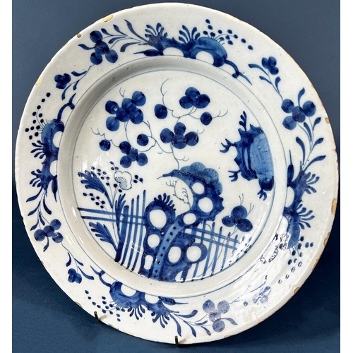 2075 - An 18th century tin glazed charger with chinoiserie style floral and picket fence detail