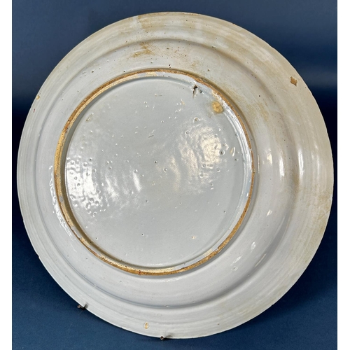 2075 - An 18th century tin glazed charger with chinoiserie style floral and picket fence detail