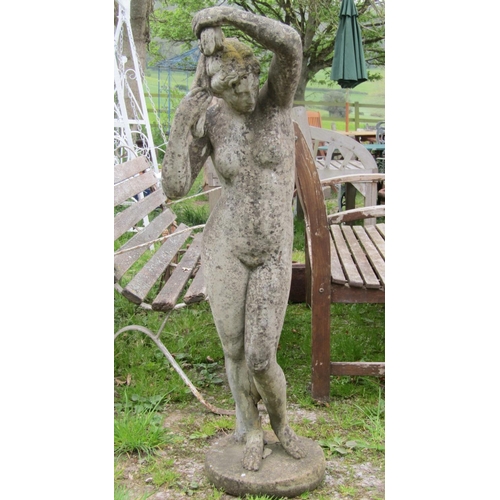 181 - A weathered cast composition stone garden ornament in the form of a standing classical maiden clutch... 