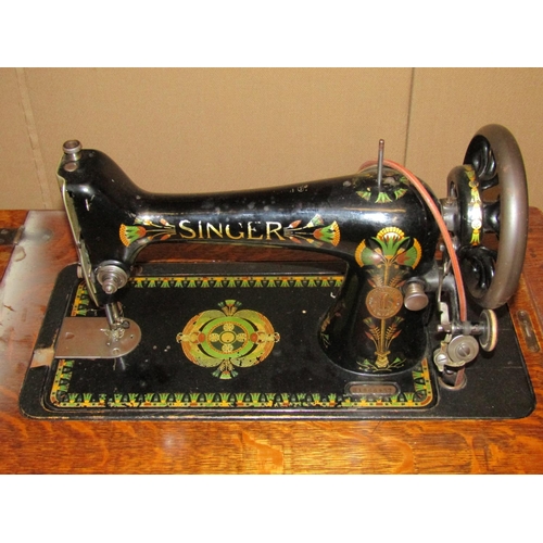 3039 - A vintage oak cased floorstanding but portable Singer sewing machine with decorative printed detail,... 