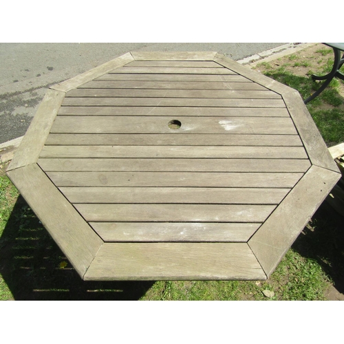 695 - A weathered teak folding garden table with octagonal slatted top 111 cm across