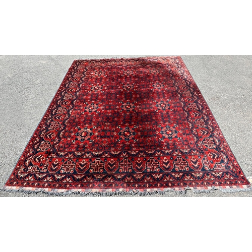 2693 - A Turkoman type carpet with an all over geometric pattern on a predominantly red ground, 280cm x 210... 