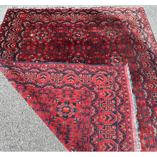 2693 - A Turkoman type carpet with an all over geometric pattern on a predominantly red ground, 280cm x 210... 