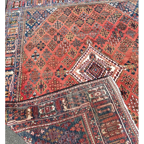 2697 - A Middle Eastern design carpet with a repeating geometric design on a pale red ground, worn in place... 