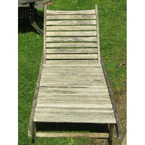 713 - A weathered teak portable two wheeled garden sun lounger with slatted seat and adjustable head rest ... 