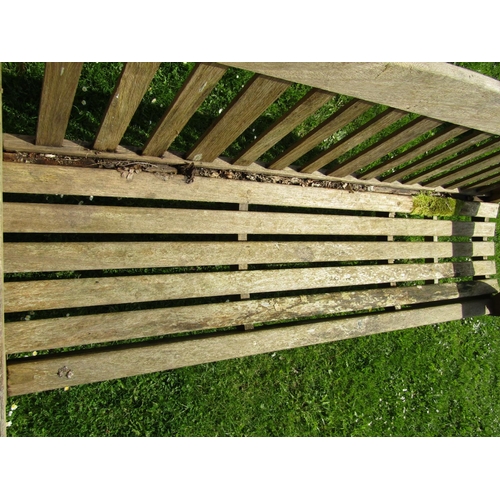 719 - A good quality heavy gauge teak three seat garden bench with slatted seat and back beneath a shaped ... 