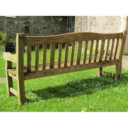 719 - A good quality heavy gauge teak three seat garden bench with slatted seat and back beneath a shaped ... 