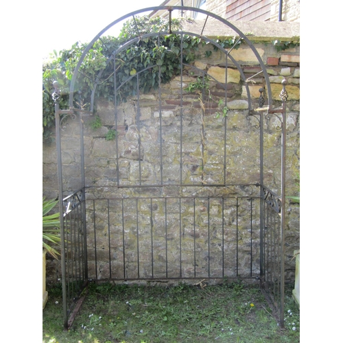 725 - A heavy gauge iron work garden arbour enclosed on three sides with simple vertical bar and open scro... 