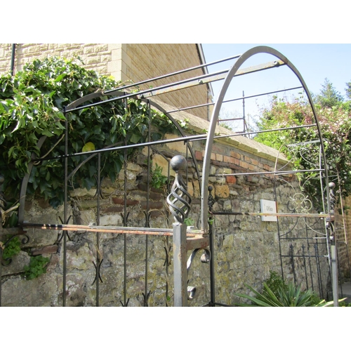 725 - A heavy gauge iron work garden arbour enclosed on three sides with simple vertical bar and open scro... 