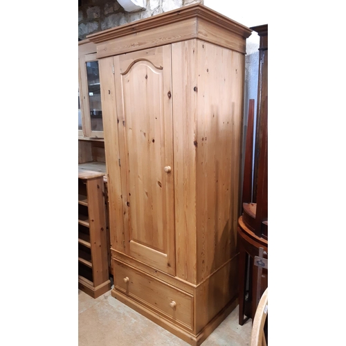 3095 - A contemporary pine wardrobe enclosed by an arched and panelled door over a single frieze drawer, 88... 