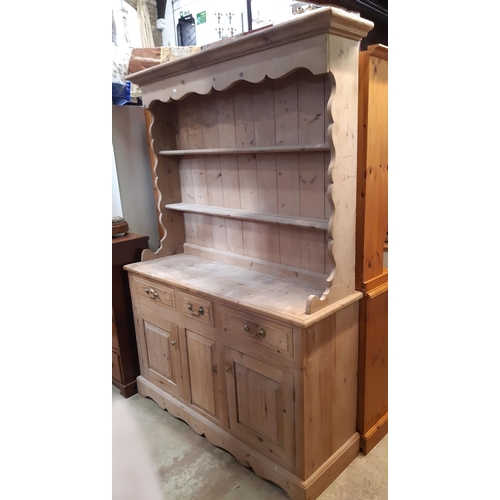 3135 - A stripped pine kitchen dresser the lower section enclosed by two cupboards and three drawers, the p... 