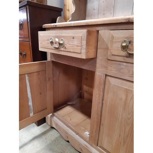 3135 - A stripped pine kitchen dresser the lower section enclosed by two cupboards and three drawers, the p... 