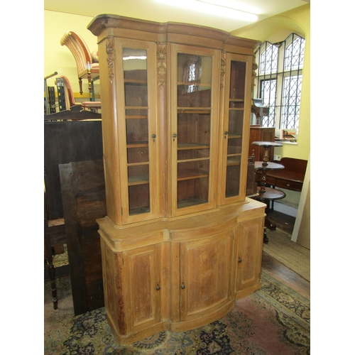 3550 - A 19th century stripped and waxed pine three door library bookcase, the lower section with bowfronte... 